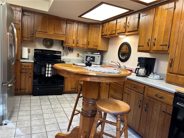 kitchen featuring light tile patterned floors, black appliances, and ventilation hood