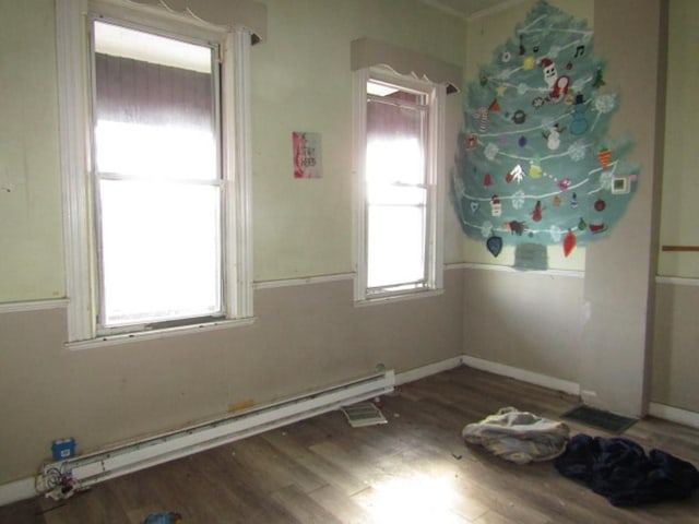 spare room featuring dark hardwood / wood-style flooring, a wealth of natural light, and a baseboard radiator