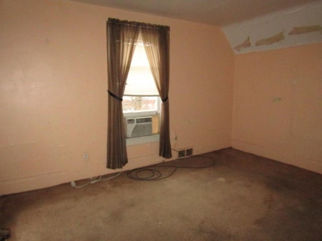 carpeted spare room featuring cooling unit and vaulted ceiling