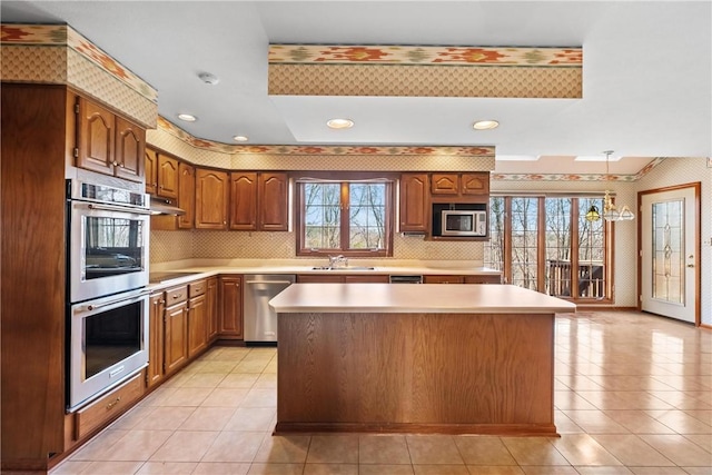 kitchen featuring a kitchen island, stainless steel appliances, light tile patterned floors, and an inviting chandelier