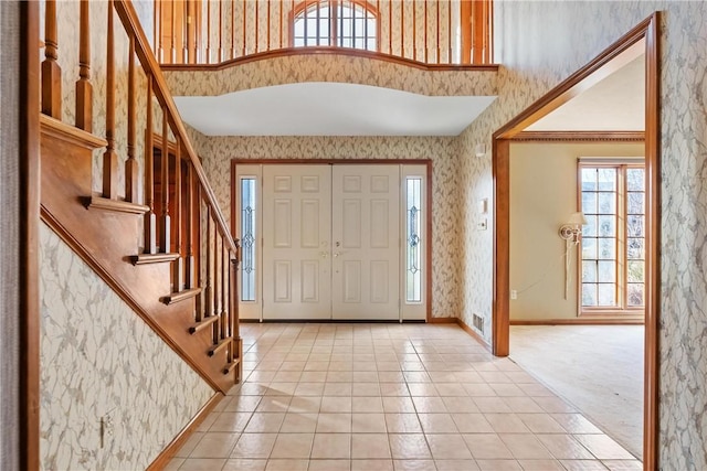 foyer entrance featuring a towering ceiling and carpet