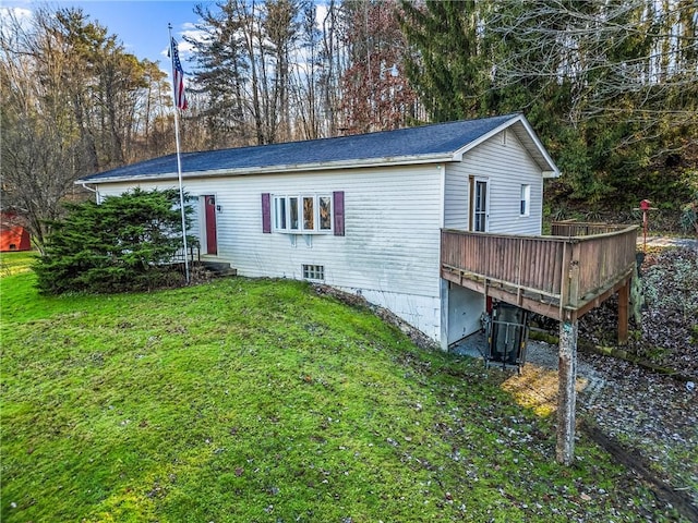 view of side of home with a wooden deck and a lawn