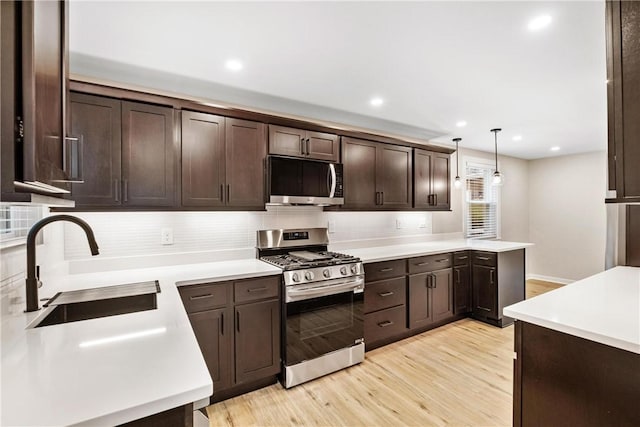 kitchen featuring pendant lighting, backsplash, sink, light hardwood / wood-style flooring, and stainless steel appliances