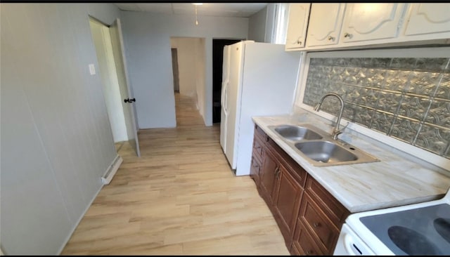 kitchen with light wood-type flooring, backsplash, sink, white fridge, and white cabinetry