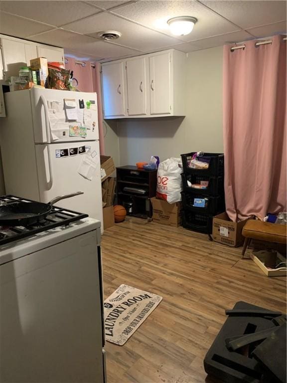 kitchen featuring a drop ceiling, white appliances, white cabinetry, and light wood-type flooring