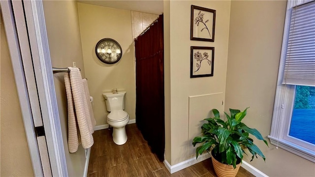 bathroom featuring curtained shower, hardwood / wood-style floors, and toilet