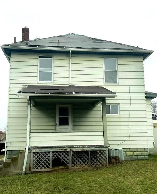 rear view of house with central air condition unit and a lawn