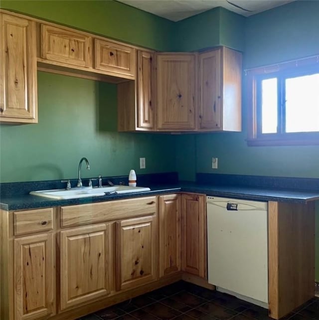 kitchen with dishwasher, dark tile patterned floors, and sink