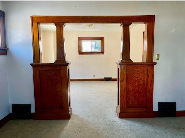 hall with ornate columns and light colored carpet