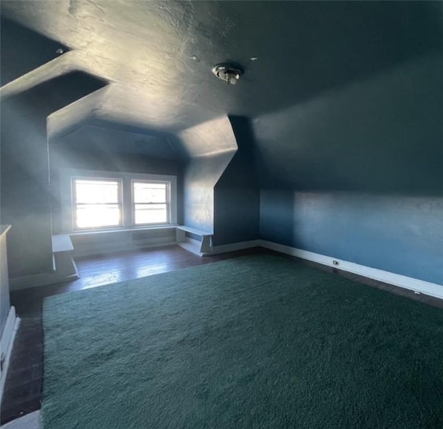 additional living space with dark carpet and lofted ceiling