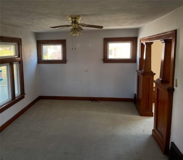 spare room featuring a wealth of natural light, ceiling fan, light colored carpet, and a textured ceiling