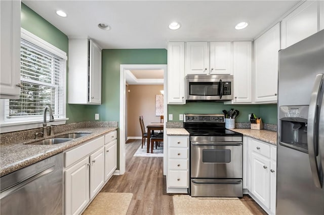 kitchen featuring white cabinetry, sink, appliances with stainless steel finishes, and light hardwood / wood-style flooring