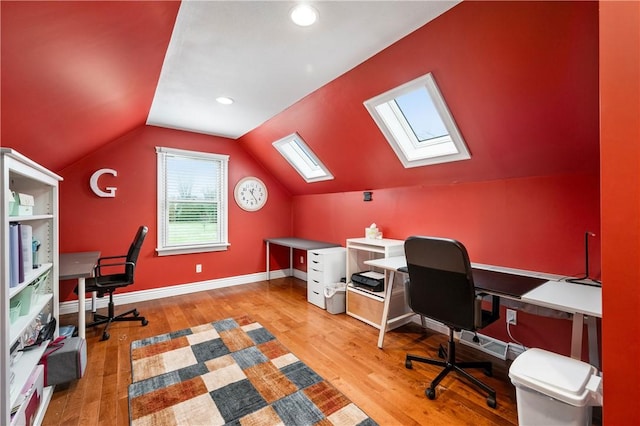 office with vaulted ceiling with skylight and light hardwood / wood-style flooring