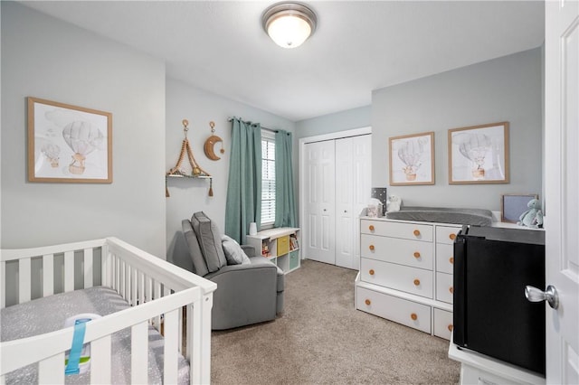 bedroom featuring light colored carpet, a crib, and a closet