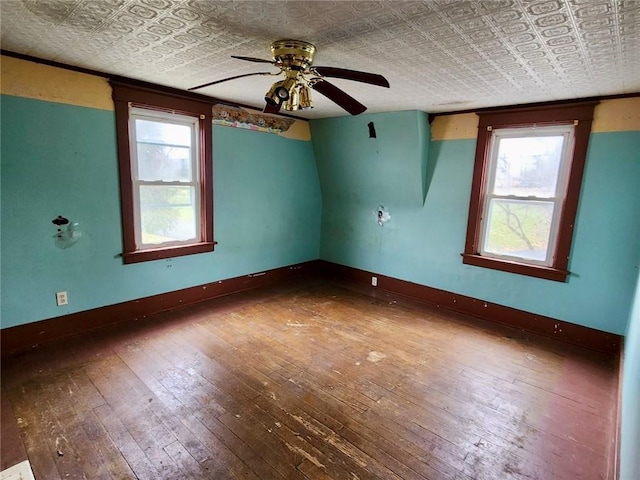 empty room with a textured ceiling, a wealth of natural light, ceiling fan, and dark hardwood / wood-style floors