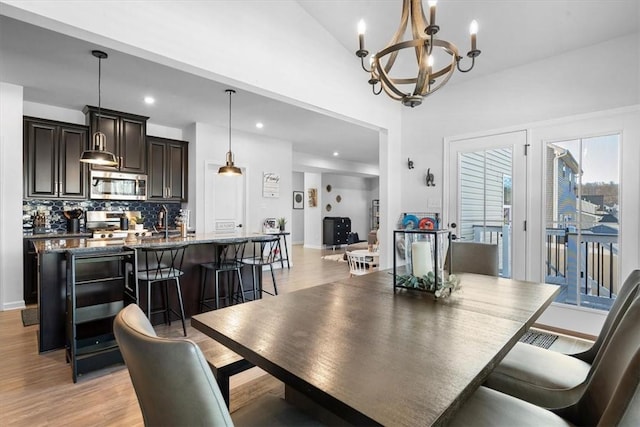 dining room featuring a chandelier, lofted ceiling, and light wood-type flooring