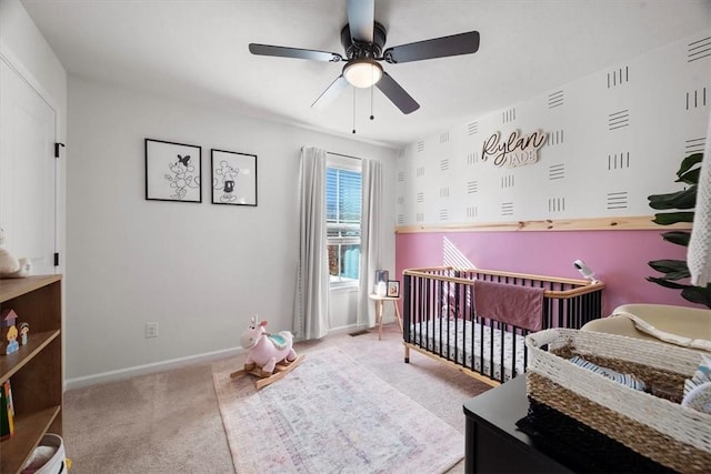 carpeted bedroom featuring ceiling fan and a nursery area