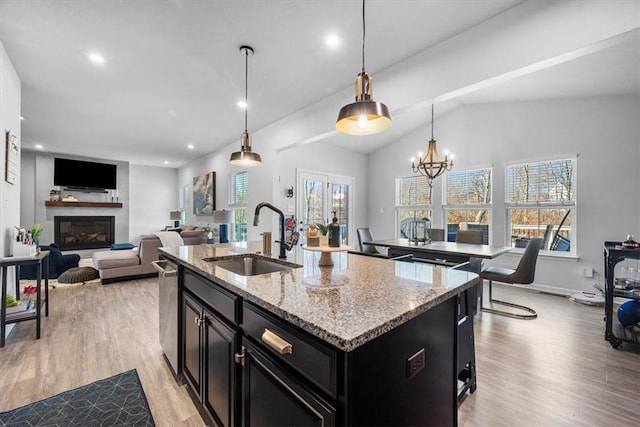 kitchen with decorative light fixtures, sink, a wealth of natural light, and an island with sink