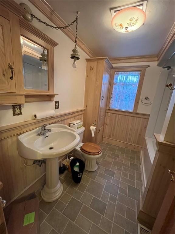 full bathroom featuring crown molding, sink, wood walls, and toilet