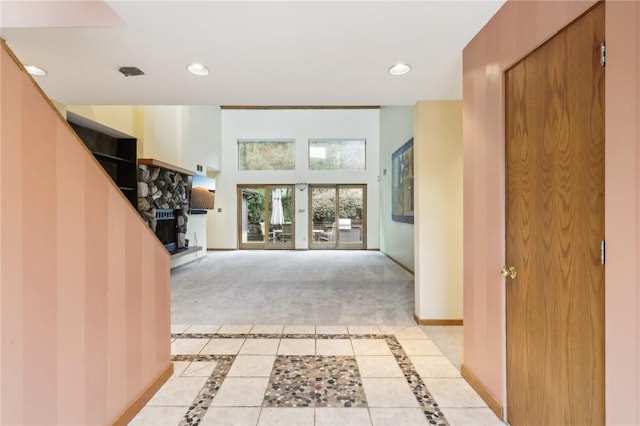 foyer entrance featuring a fireplace, light tile patterned floors, and french doors