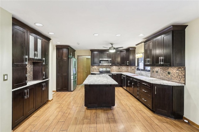 kitchen with ceiling fan, sink, a center island, stainless steel appliances, and light hardwood / wood-style floors