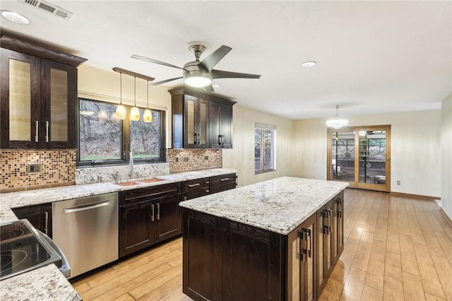 kitchen featuring tasteful backsplash, stainless steel dishwasher, sink, decorative light fixtures, and a center island