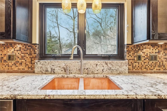 kitchen with decorative backsplash, light stone counters, a healthy amount of sunlight, and sink