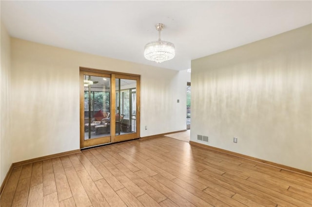 unfurnished room with a healthy amount of sunlight, a chandelier, and light wood-type flooring