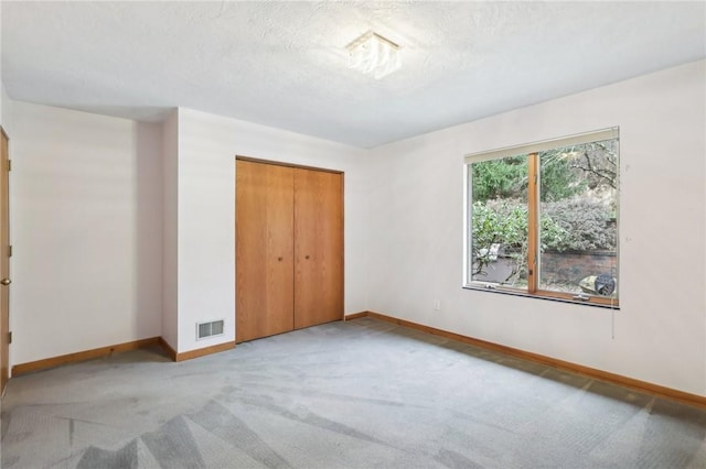 unfurnished bedroom featuring light carpet and a closet