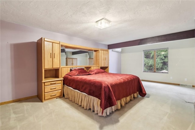 bedroom with a textured ceiling, light carpet, and a wall mounted air conditioner