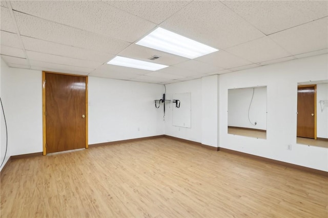 basement with wood-type flooring and a paneled ceiling