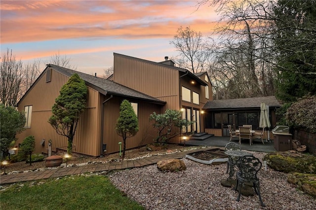 back house at dusk featuring a patio area