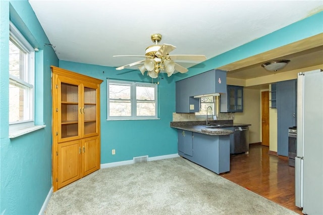 kitchen with kitchen peninsula, a wealth of natural light, sink, and dark carpet