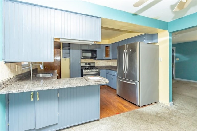 kitchen with kitchen peninsula, appliances with stainless steel finishes, backsplash, blue cabinetry, and hardwood / wood-style flooring