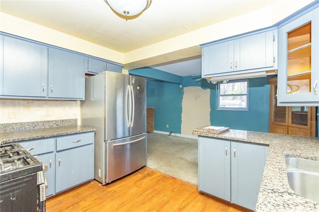 kitchen featuring blue cabinetry, stainless steel refrigerator, light stone countertops, and light hardwood / wood-style flooring