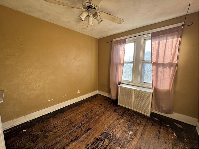 spare room with ceiling fan, radiator heating unit, and dark wood-type flooring