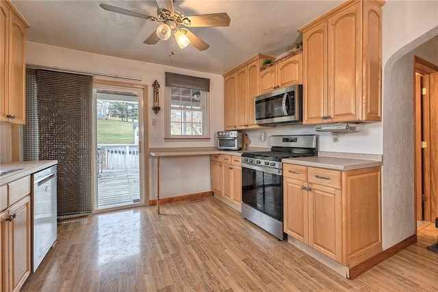 kitchen with light brown cabinetry, ceiling fan, light hardwood / wood-style flooring, and appliances with stainless steel finishes