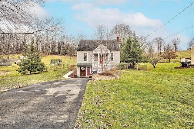 view of front of house with a rural view and a front lawn