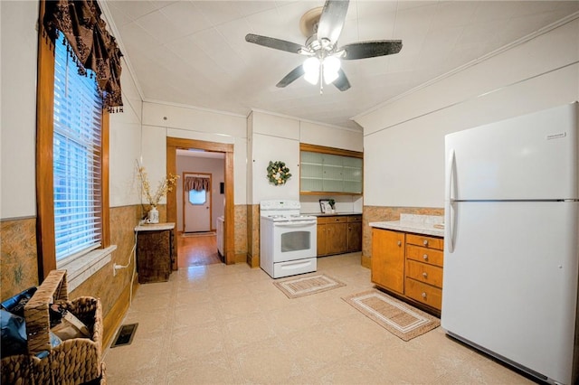 kitchen featuring white appliances, wood walls, ceiling fan, and crown molding