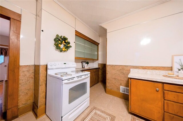 kitchen with white electric range, tile walls, and crown molding