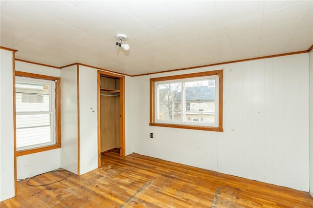 unfurnished bedroom featuring light wood-type flooring, crown molding, and a closet