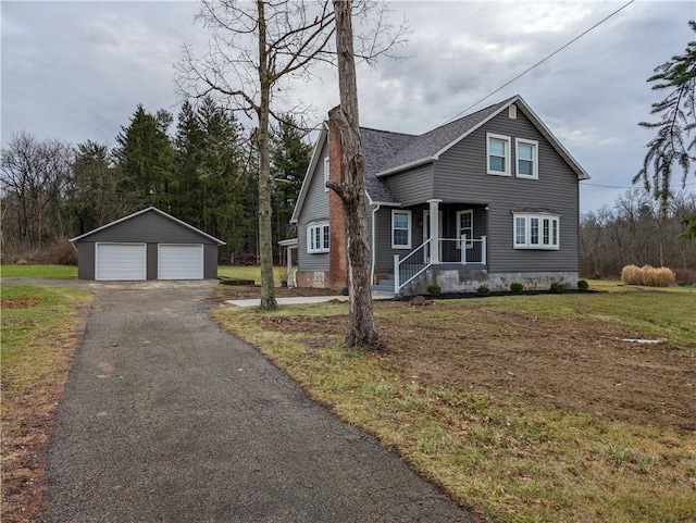 view of property featuring a garage, an outdoor structure, and a front lawn