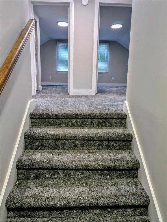 stairs with a wealth of natural light, carpet floors, and lofted ceiling