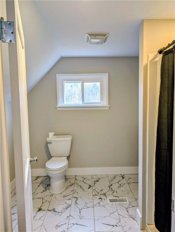 bathroom featuring vaulted ceiling and toilet