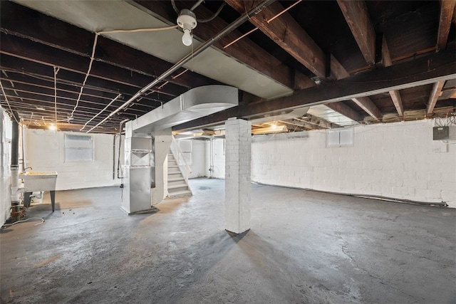 basement featuring sink, heating unit, and electric panel