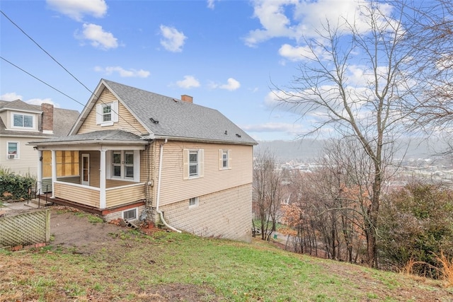 back of property featuring a yard and covered porch