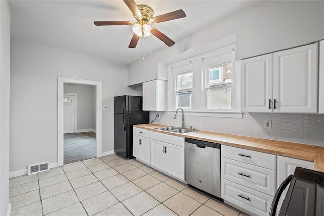 kitchen featuring white cabinetry, butcher block counters, sink, stainless steel dishwasher, and black fridge