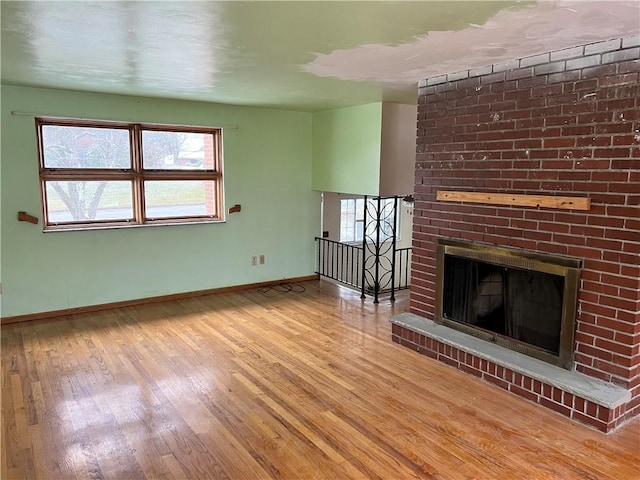 unfurnished living room featuring light hardwood / wood-style floors and a brick fireplace