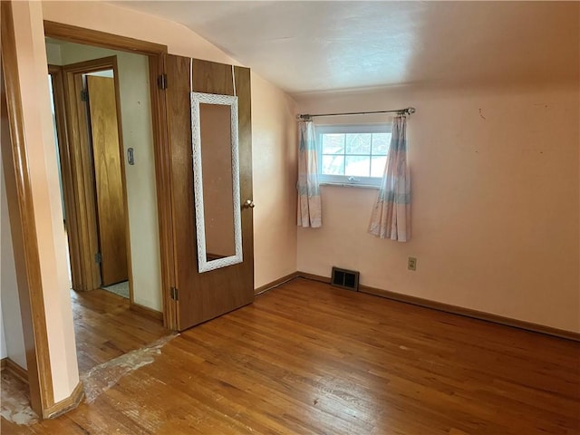 unfurnished room with hardwood / wood-style floors and lofted ceiling