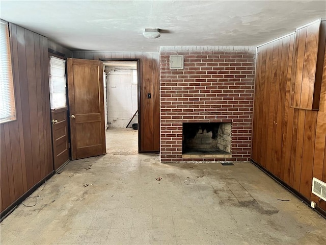 unfurnished living room with wooden walls and a brick fireplace